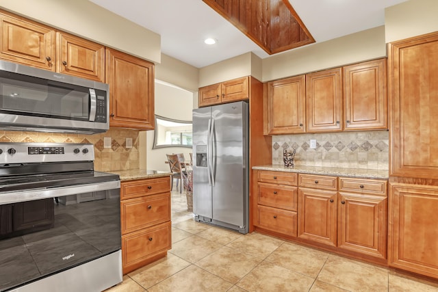 kitchen featuring appliances with stainless steel finishes, brown cabinetry, and light stone counters