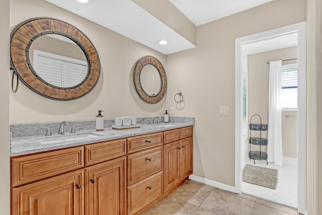 bathroom featuring baseboards, double vanity, a sink, and tile patterned floors