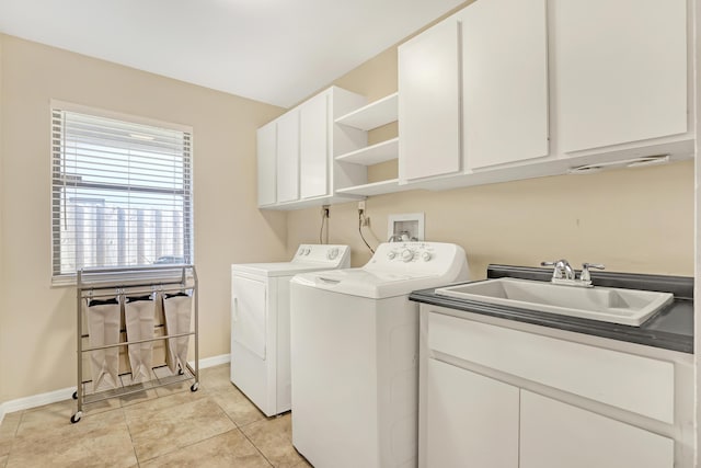 clothes washing area featuring light tile patterned flooring, a sink, baseboards, washer and dryer, and cabinet space