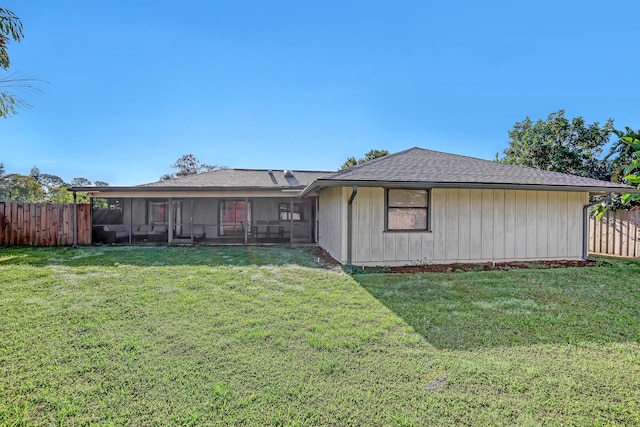 back of house featuring a lawn, fence, and a sunroom