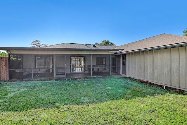 back of property featuring a sunroom, a shingled roof, and a lawn