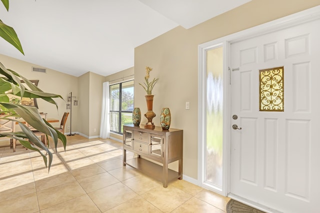 entryway with light tile patterned floors, vaulted ceiling, visible vents, and baseboards