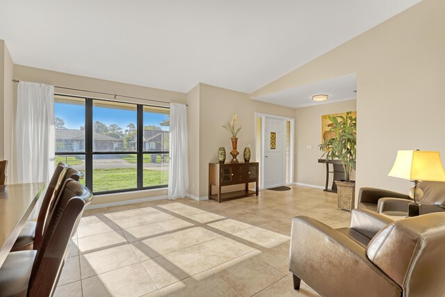 living area featuring vaulted ceiling, baseboards, and light tile patterned floors