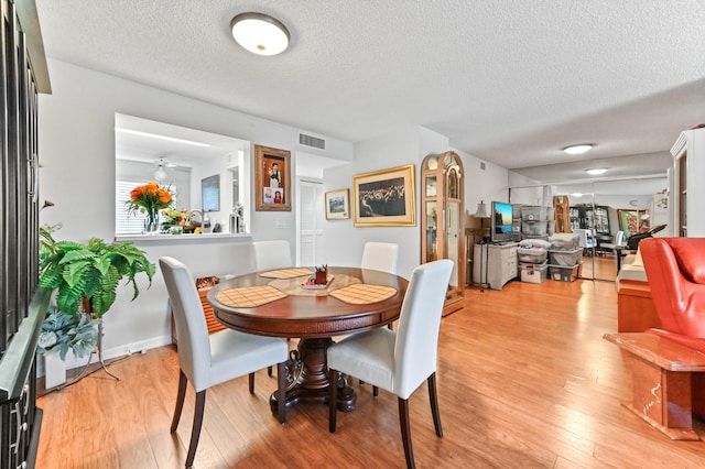 dining area with light hardwood / wood-style floors and a textured ceiling