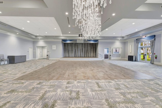 unfurnished living room featuring carpet, a notable chandelier, and a tray ceiling