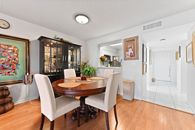 dining space with a textured ceiling and light wood-type flooring