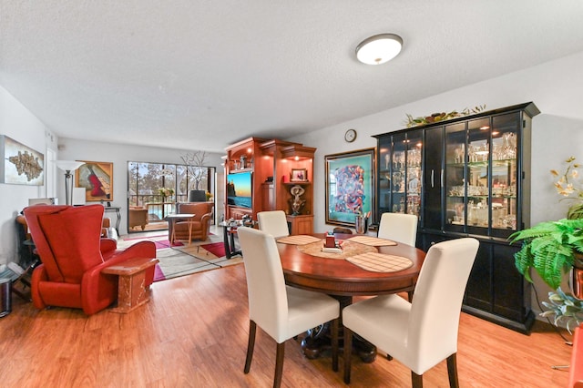 dining space featuring wood-type flooring and a textured ceiling