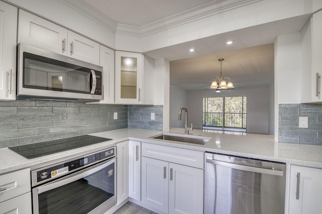 7281 Amberly Ln Unit 306, Delray Beach, FL 33446 - kitchen featuring appliances with stainless steel finishes, a sink, ornamental molding, a chandelier, and white cabinetry
