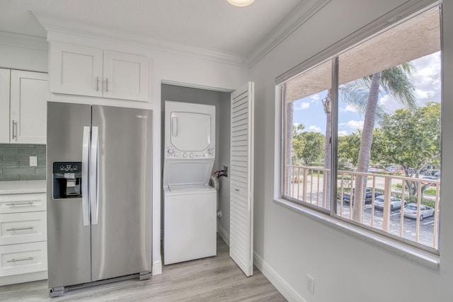 7281 Amberly Ln Unit 306, Delray Beach, FL 33446 - kitchen with stainless steel refrigerator with ice dispenser, estacked washer and dryer, crown molding, white cabinetry, and healthy amount of natural light