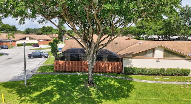 view of front of house featuring a lanai and a front lawn