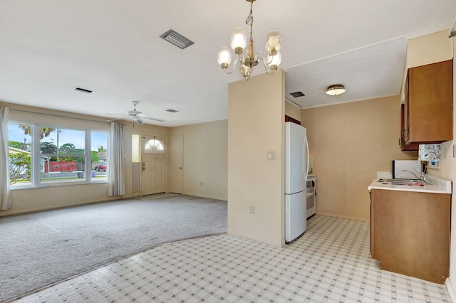 kitchen with brown cabinets, visible vents, light countertops, freestanding refrigerator, and open floor plan