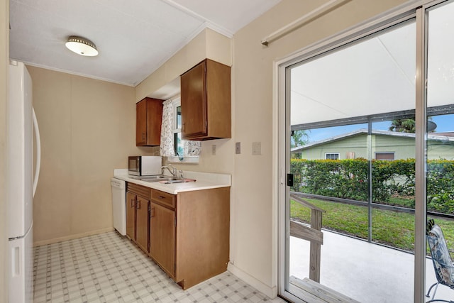 kitchen with light floors, light countertops, brown cabinetry, dishwasher, and fridge