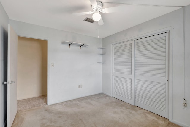 unfurnished bedroom featuring a ceiling fan, a closet, visible vents, and light colored carpet