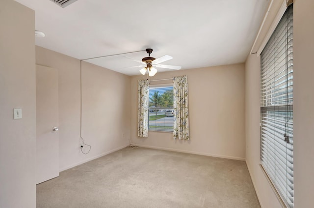 carpeted spare room featuring baseboards and a ceiling fan