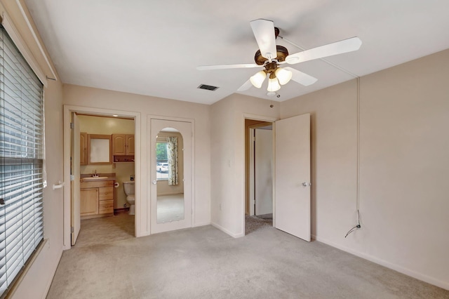 unfurnished bedroom with light carpet, visible vents, arched walkways, ensuite bath, and a sink