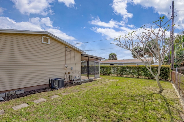 view of yard with a fenced backyard, a sunroom, and central air condition unit