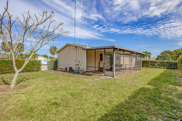 rear view of house with a sunroom, a lawn, fence, and central AC unit