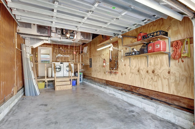 garage with a garage door opener, wood walls, washing machine and clothes dryer, and a workshop area