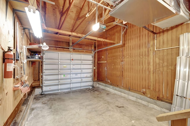 garage with a garage door opener and wood walls