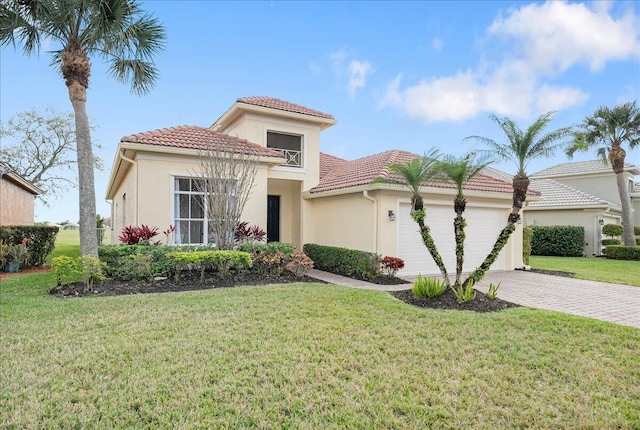 mediterranean / spanish house with decorative driveway, a front yard, a tiled roof, and an attached garage