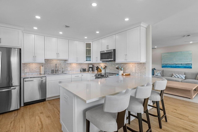 kitchen with stainless steel appliances, a kitchen bar, sink, and white cabinets