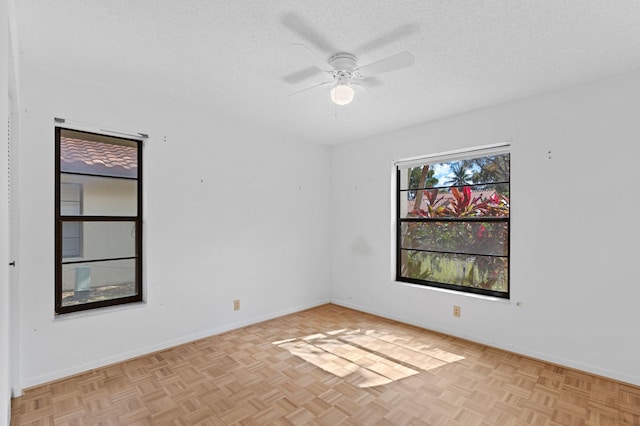 empty room featuring ceiling fan, a textured ceiling, and light parquet floors