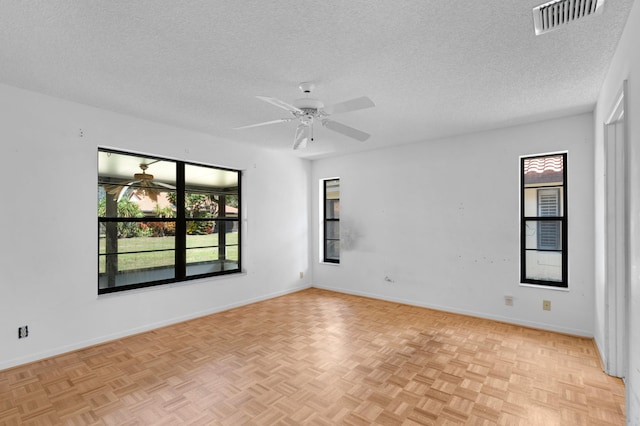 empty room with light parquet floors, ceiling fan, and a textured ceiling