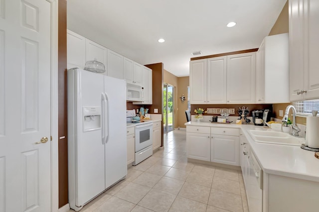 kitchen featuring white cabinetry, sink, light tile patterned floors, and white appliances