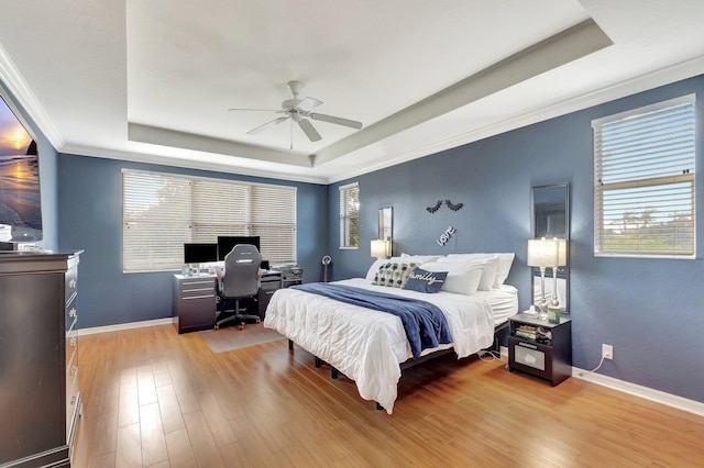 bedroom with ornamental molding, a raised ceiling, and hardwood / wood-style floors