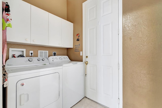 laundry area featuring cabinets, light tile patterned floors, and washing machine and clothes dryer