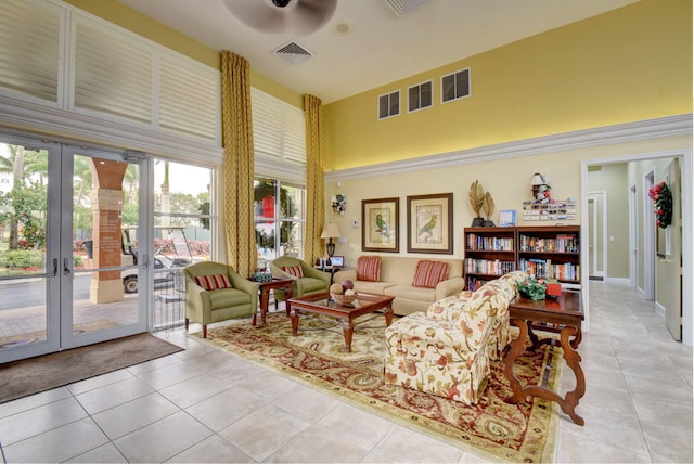 living room with a towering ceiling, ceiling fan, and light tile patterned flooring