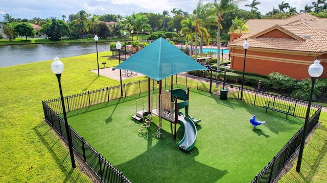 view of home's community with a playground, a water view, and a yard