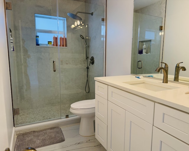 bathroom featuring vanity, a shower with shower door, and toilet