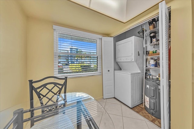 clothes washing area featuring light tile patterned floors and stacked washer / dryer