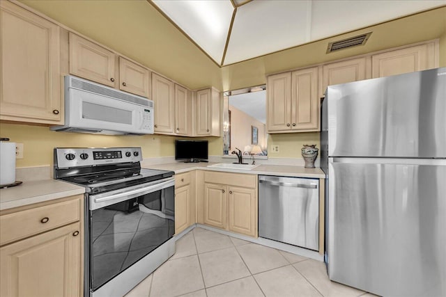 kitchen featuring light brown cabinetry, sink, light tile patterned floors, and appliances with stainless steel finishes