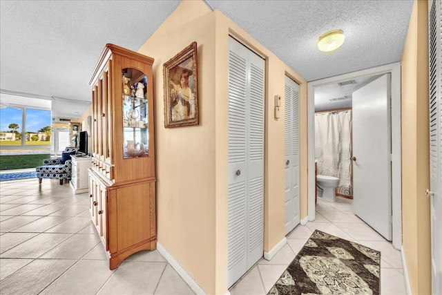 hall featuring a textured ceiling and light tile patterned floors