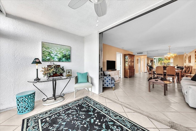 living room featuring tile patterned flooring, ceiling fan with notable chandelier, and a textured ceiling