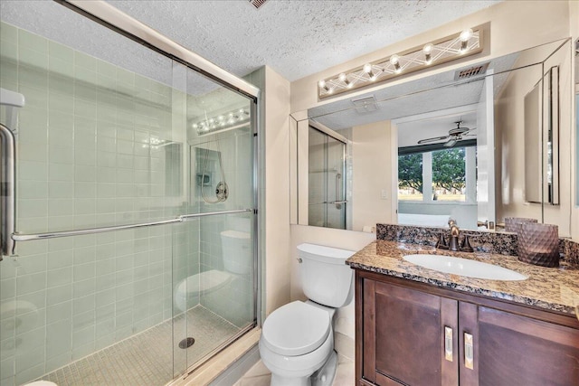 bathroom featuring vanity, ceiling fan, toilet, a shower with door, and a textured ceiling