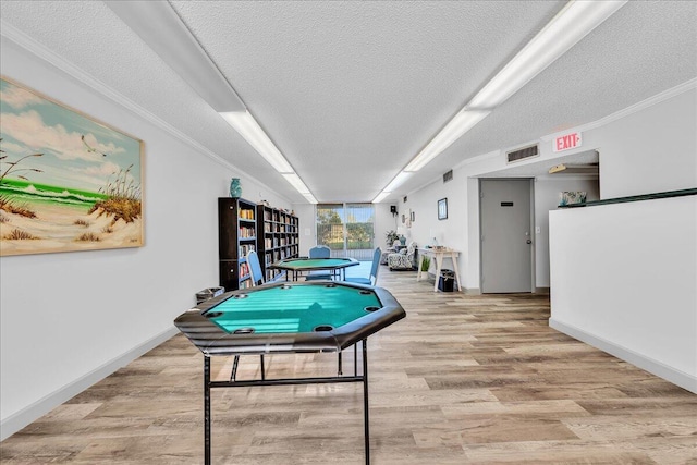 recreation room featuring crown molding, a textured ceiling, and light wood-type flooring