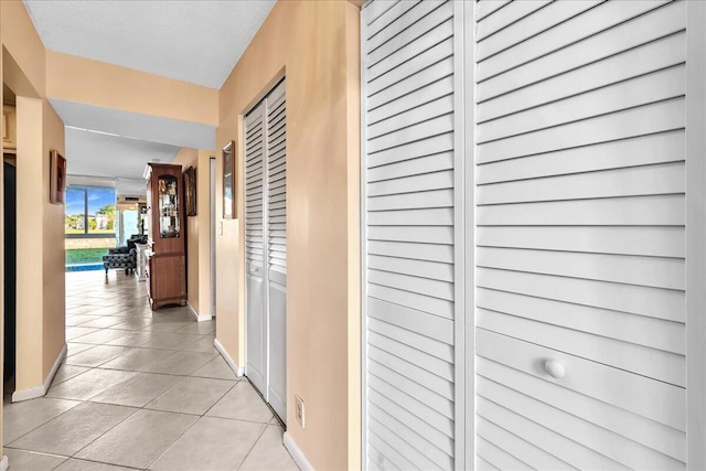 corridor featuring light tile patterned floors and a textured ceiling