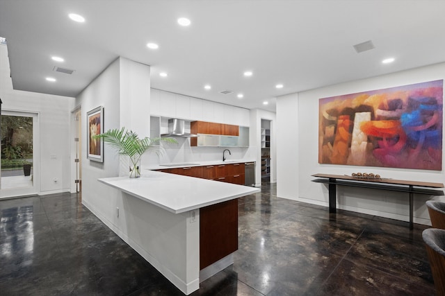 kitchen featuring wall chimney exhaust hood, sink, white cabinetry, stainless steel dishwasher, and kitchen peninsula