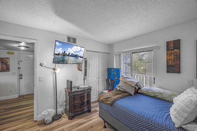 bedroom with wood-type flooring, a closet, and a textured ceiling