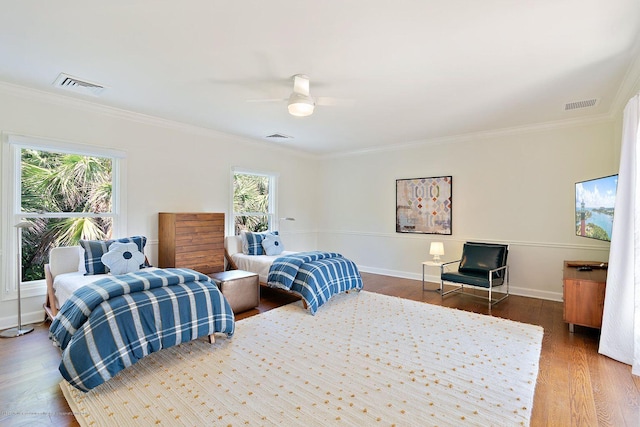 bedroom featuring dark wood-type flooring, ornamental molding, and ceiling fan