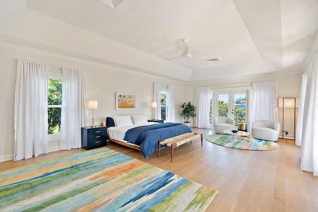 bedroom featuring french doors, ornamental molding, a tray ceiling, access to exterior, and hardwood / wood-style floors