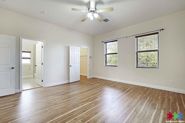 unfurnished bedroom featuring ceiling fan, a spacious closet, connected bathroom, and light hardwood / wood-style floors