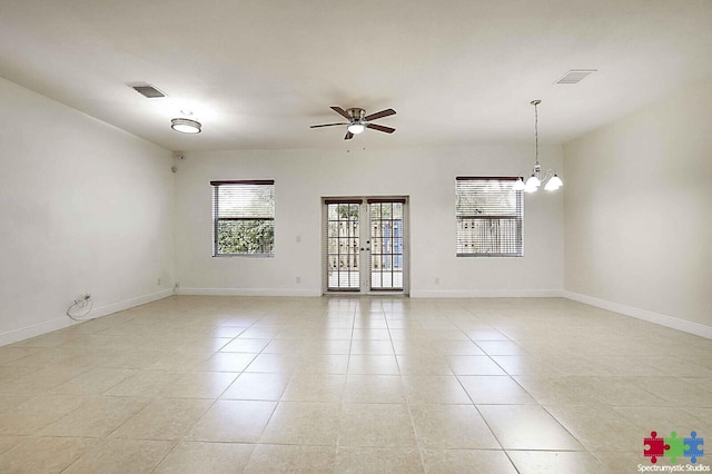 unfurnished room featuring ceiling fan with notable chandelier, french doors, and light tile patterned flooring