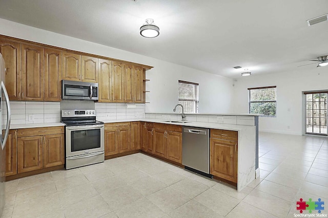 kitchen featuring tasteful backsplash, sink, ceiling fan, kitchen peninsula, and stainless steel appliances