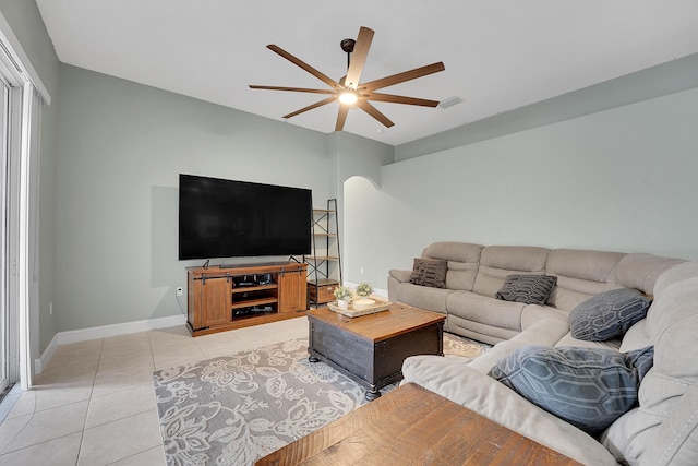 living area with arched walkways, ceiling fan, light tile patterned flooring, visible vents, and baseboards