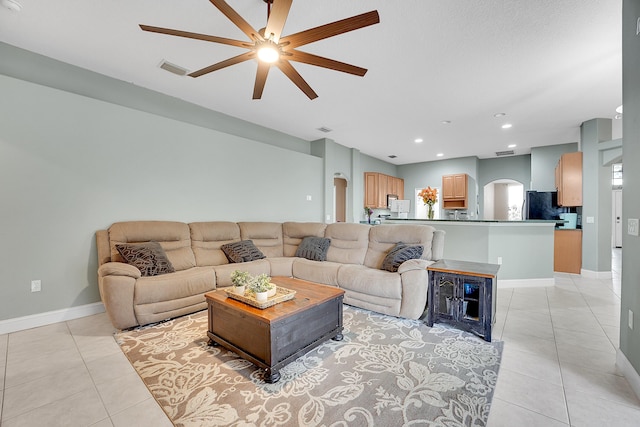 living area featuring light tile patterned floors, baseboards, visible vents, and arched walkways