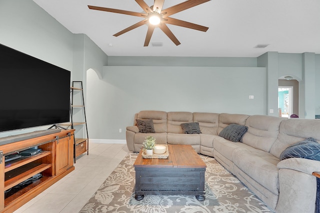 living area featuring arched walkways, light tile patterned floors, visible vents, ceiling fan, and baseboards